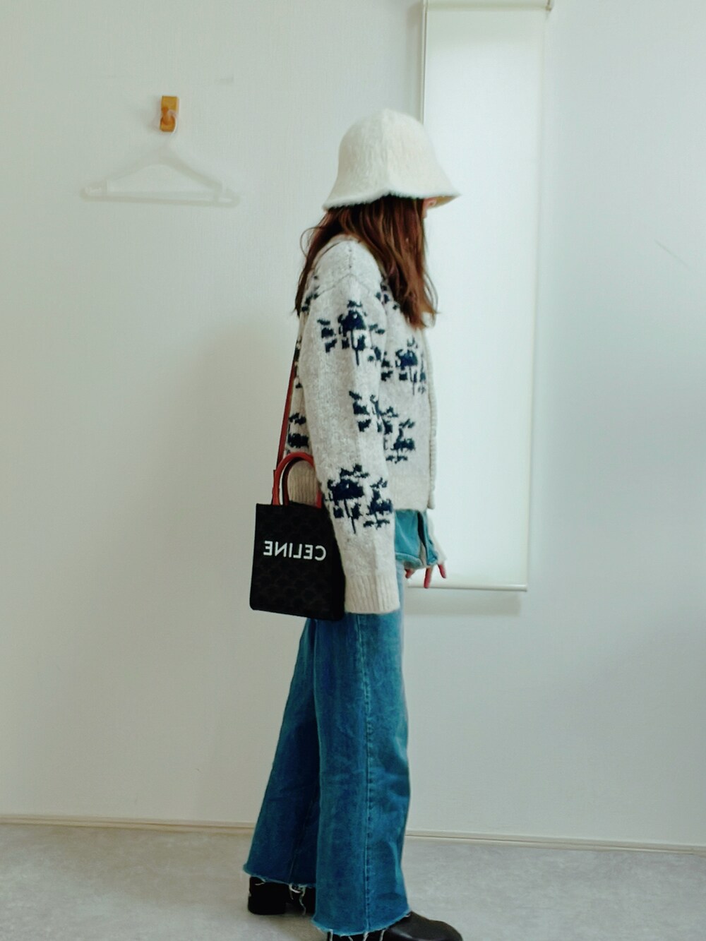 ホワイト系のカーディガン/ボレロ、ブルー系のデニムパンツ、ブラウン系のブーツを着用したレディースの冬コーディネートの2枚目の写真