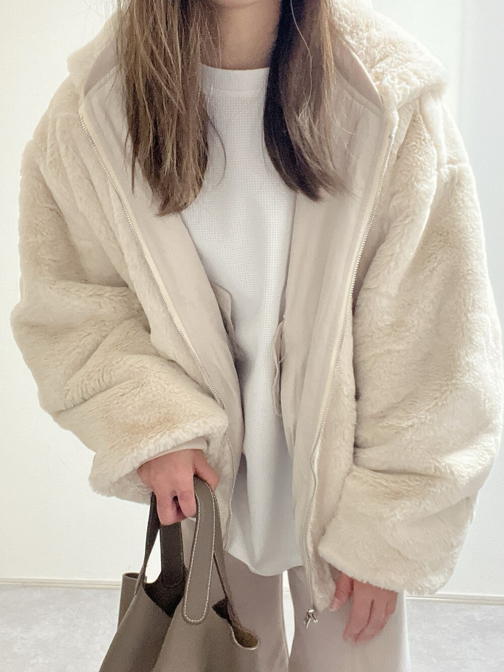 ベージュ系のブルゾン、ベージュ系のスニーカー、ホワイト系のパンツを着用したレディースの冬コーディネートの3枚目の写真