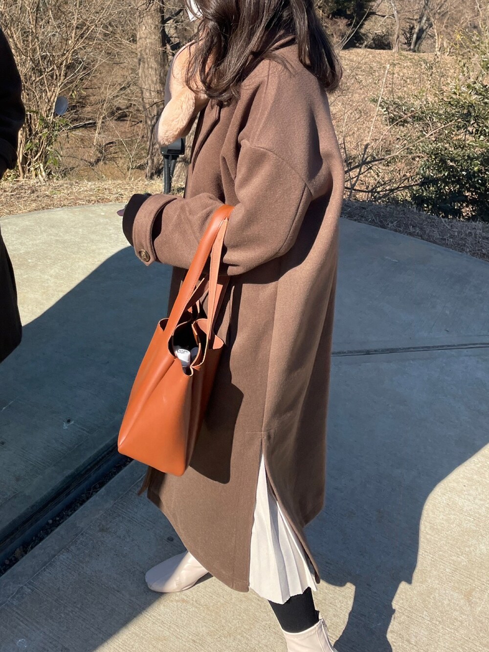 ブラウン系のジャケット/アウター、ホワイト系のブーツ、ブラウン系のバッグを着用したレディースの冬コーディネートの2枚目の写真