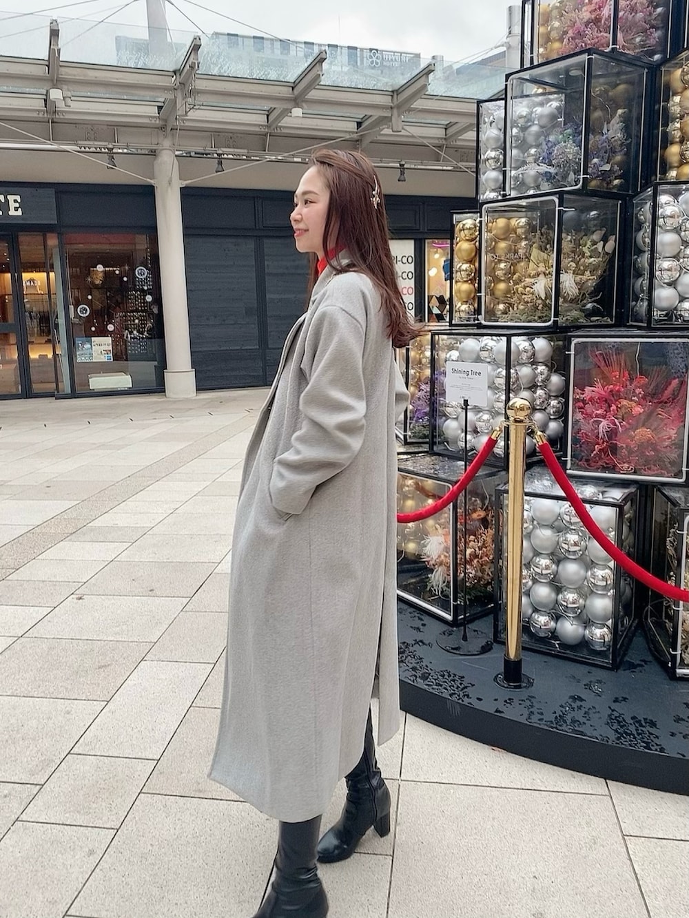 グレー系のチェスターコート、ベージュ系のショルダーバッグを着用したレディースの春コーディネートの2枚目の写真