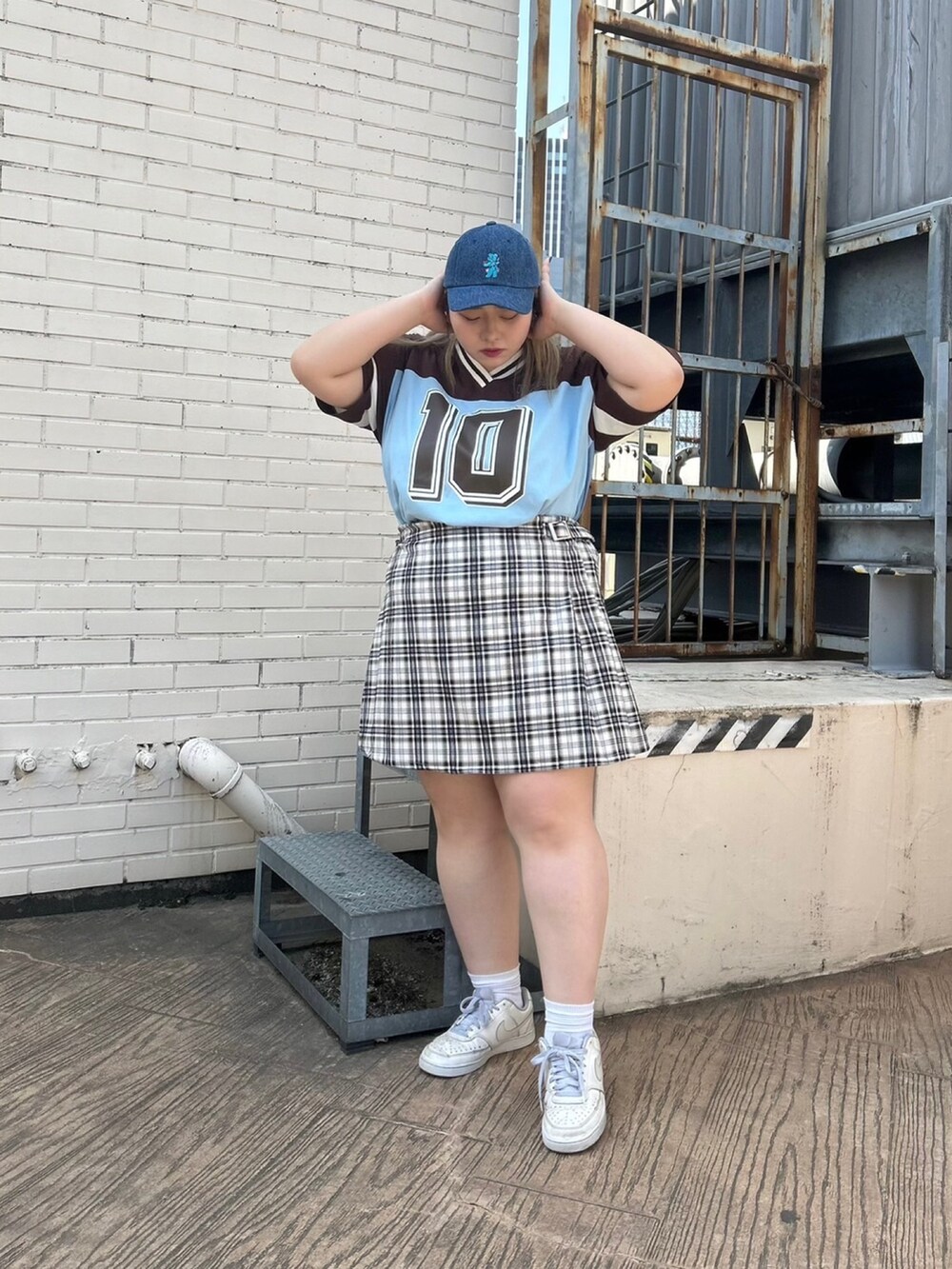 ブラウン系のTシャツ/カットソー、ブラック系のスカート、ブルー系のキャップを着用したレディースの春コーディネートの2枚目の写真