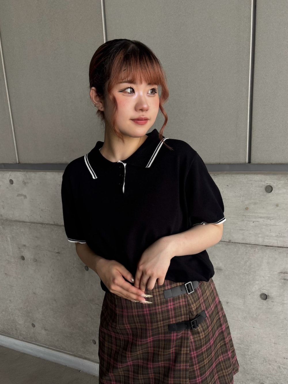 グリーン系のスカート、ブラック系のポロシャツを着用したレディースの夏コーディネートの3枚目の写真