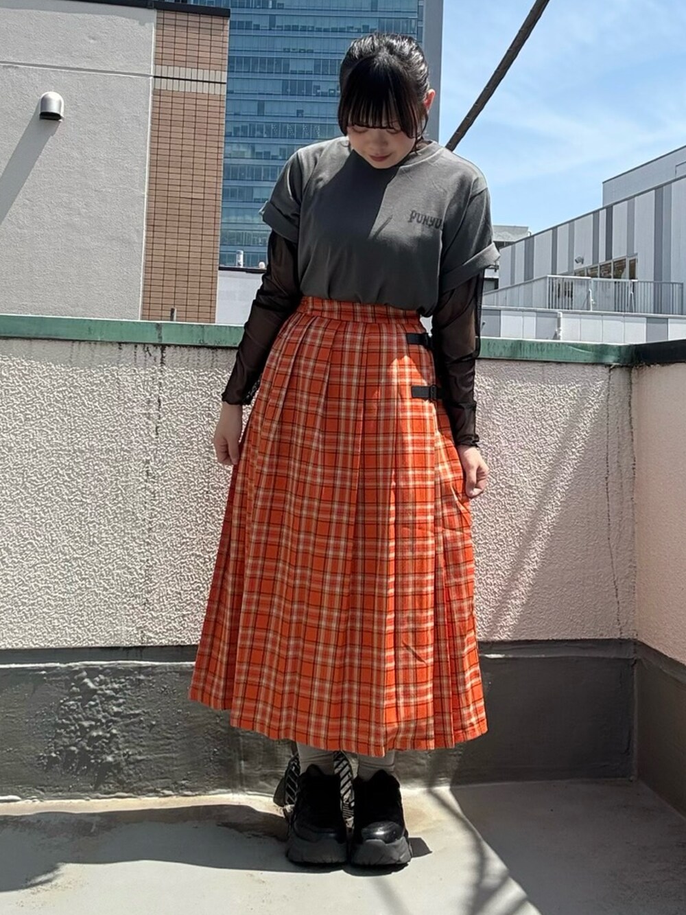 オレンジ系のスカート、ブラック系のTシャツ/カットソー、ブラック系のTシャツ/カットソーを着用したレディースの春コーディネートの3枚目の写真