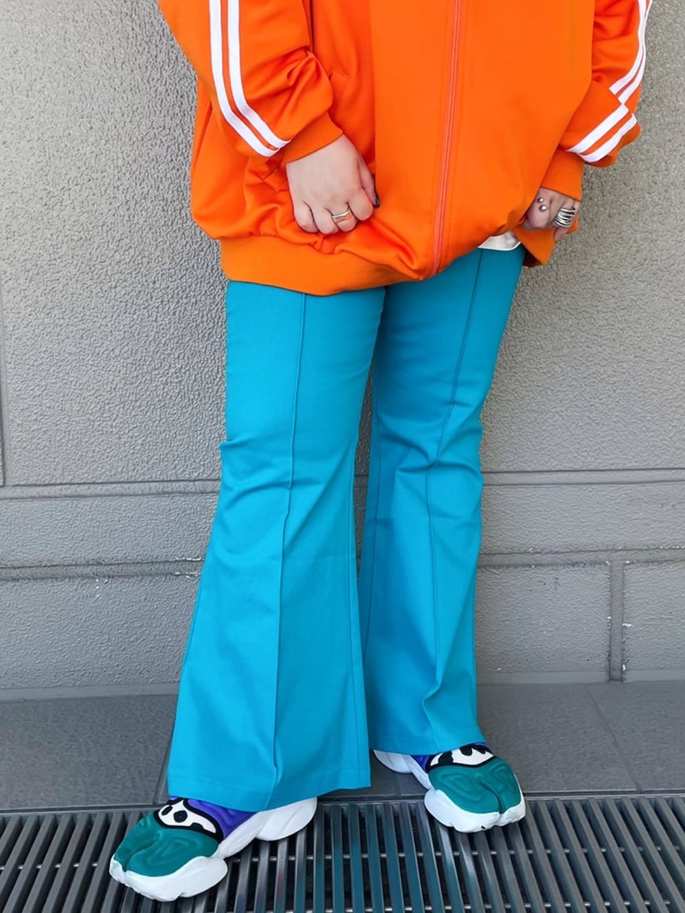 グリーン系のその他パンツ、オレンジ系のジャージを着用したレディースの春コーディネートの2枚目の写真