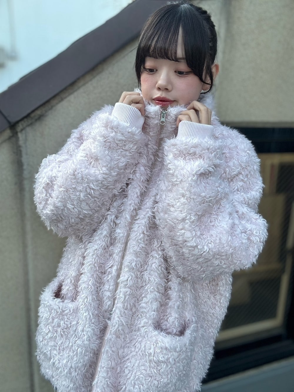 ピンク系のブルゾン、グレー系のニット/セーター、グレー系のスカートを着用したレディースの冬コーディネートの3枚目の写真