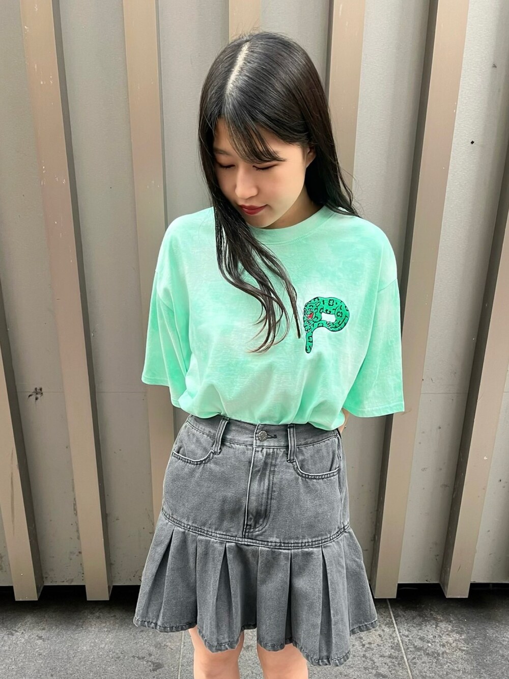 グリーン系のTシャツ/カットソー、ブラック系のデニムスカート、ブラック系のサンダルを着用したレディースの春コーディネートの2枚目の写真