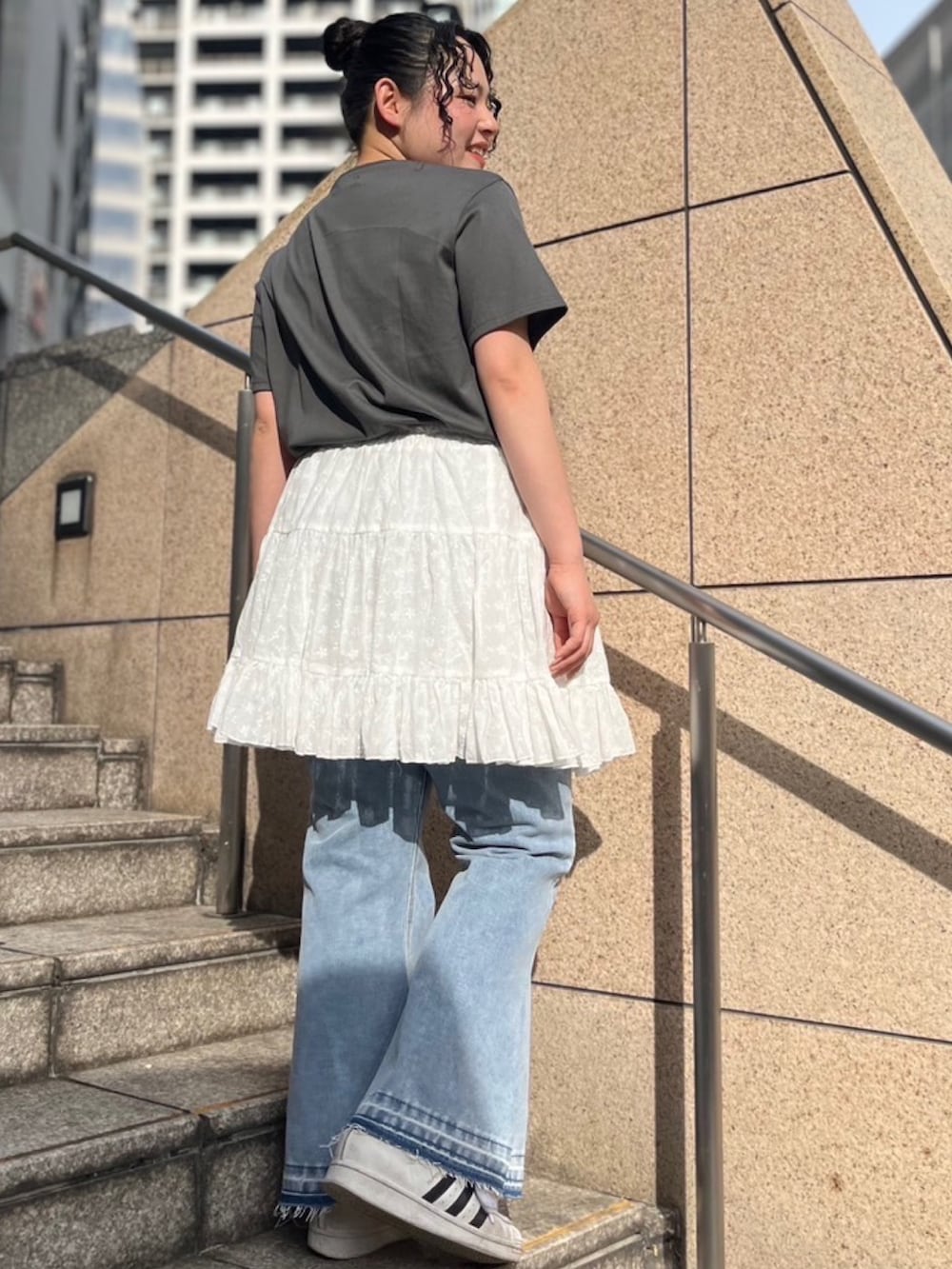 ブルー系のデニムパンツ、ホワイト系のスカート、ブラック系のTシャツ/カットソーを着用したレディースの春コーディネートの2枚目の写真