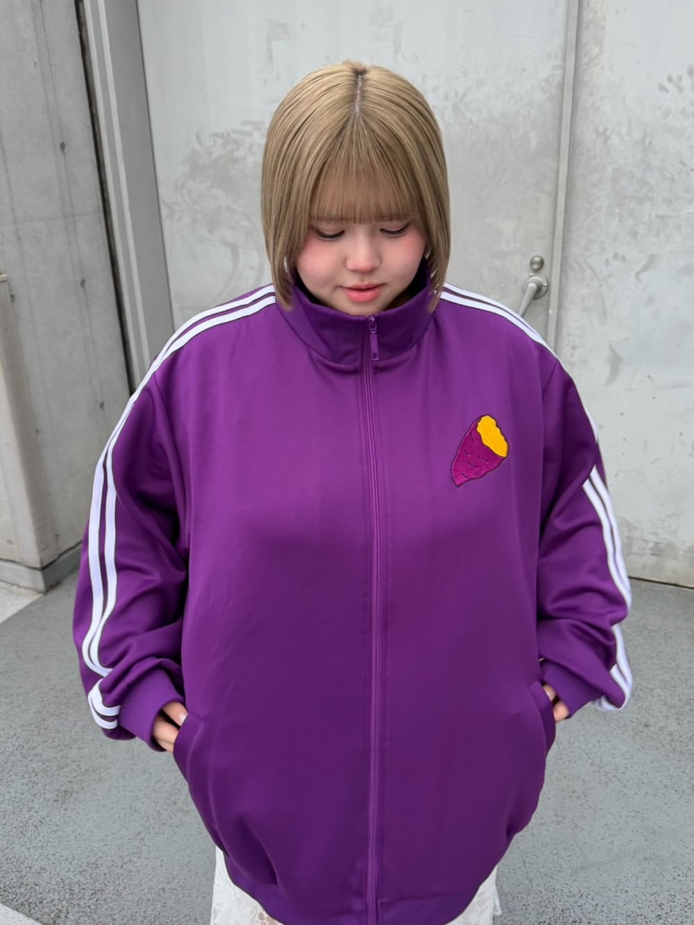 パープル系のジャージ、ホワイト系のスカートを着用したレディースの秋コーディネートの5枚目の写真
