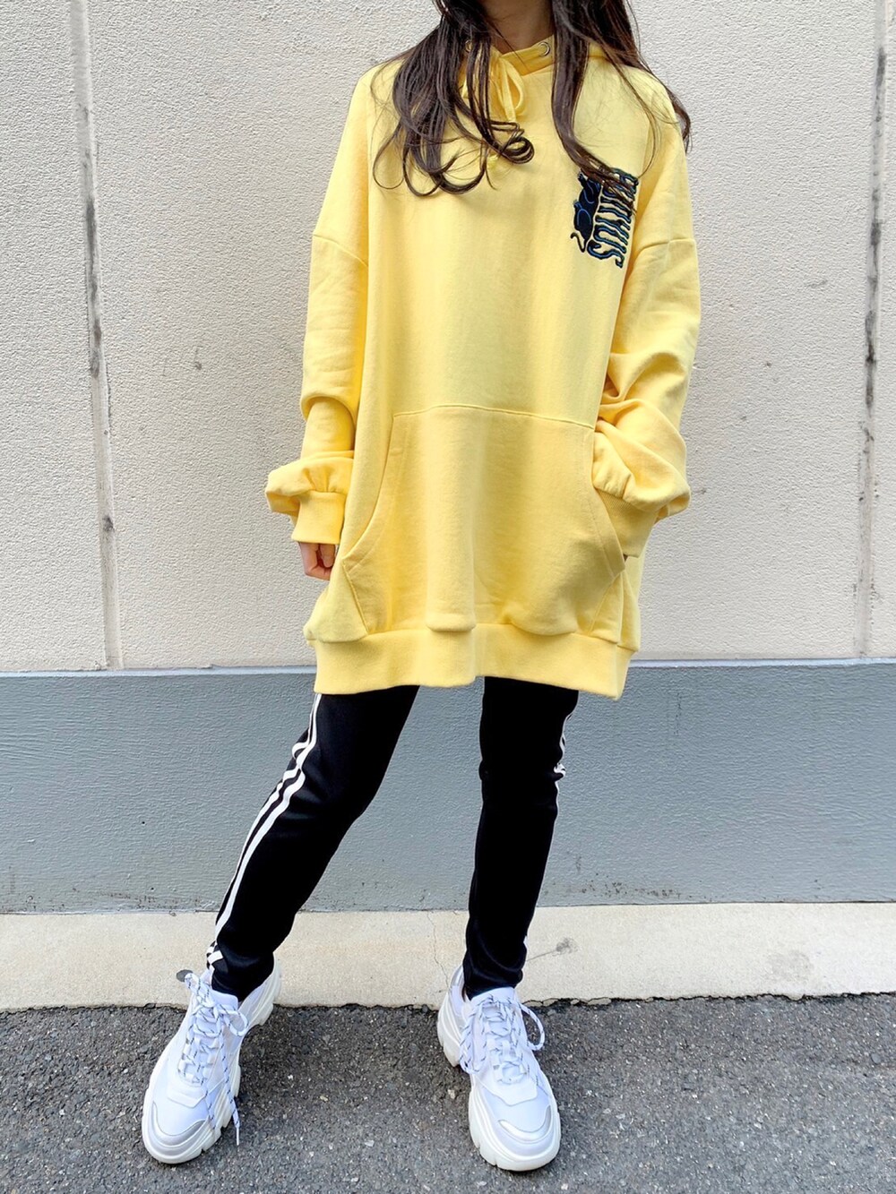 イエロー系のパーカー、ブラック系のダウンジャケット/コート、ホワイト系のレギンス/スパッツを着用したレディースの冬コーディネートの3枚目の写真