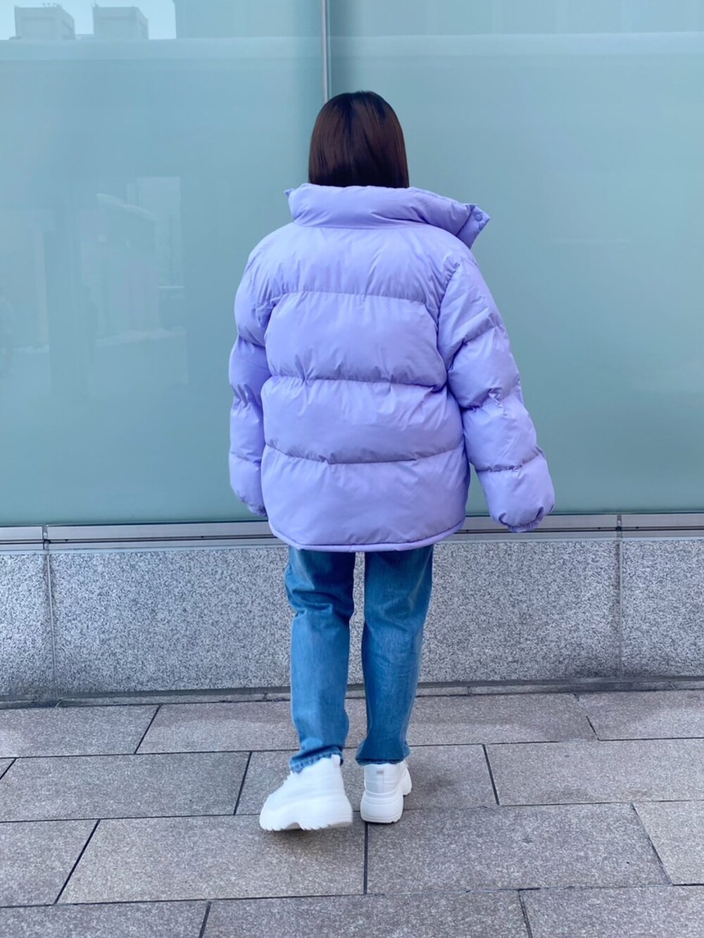 パープル系のダウンジャケット/コート、グリーン系のニット/セーター、ブルー系のデニムパンツを着用したレディースの冬コーディネートの3枚目の写真