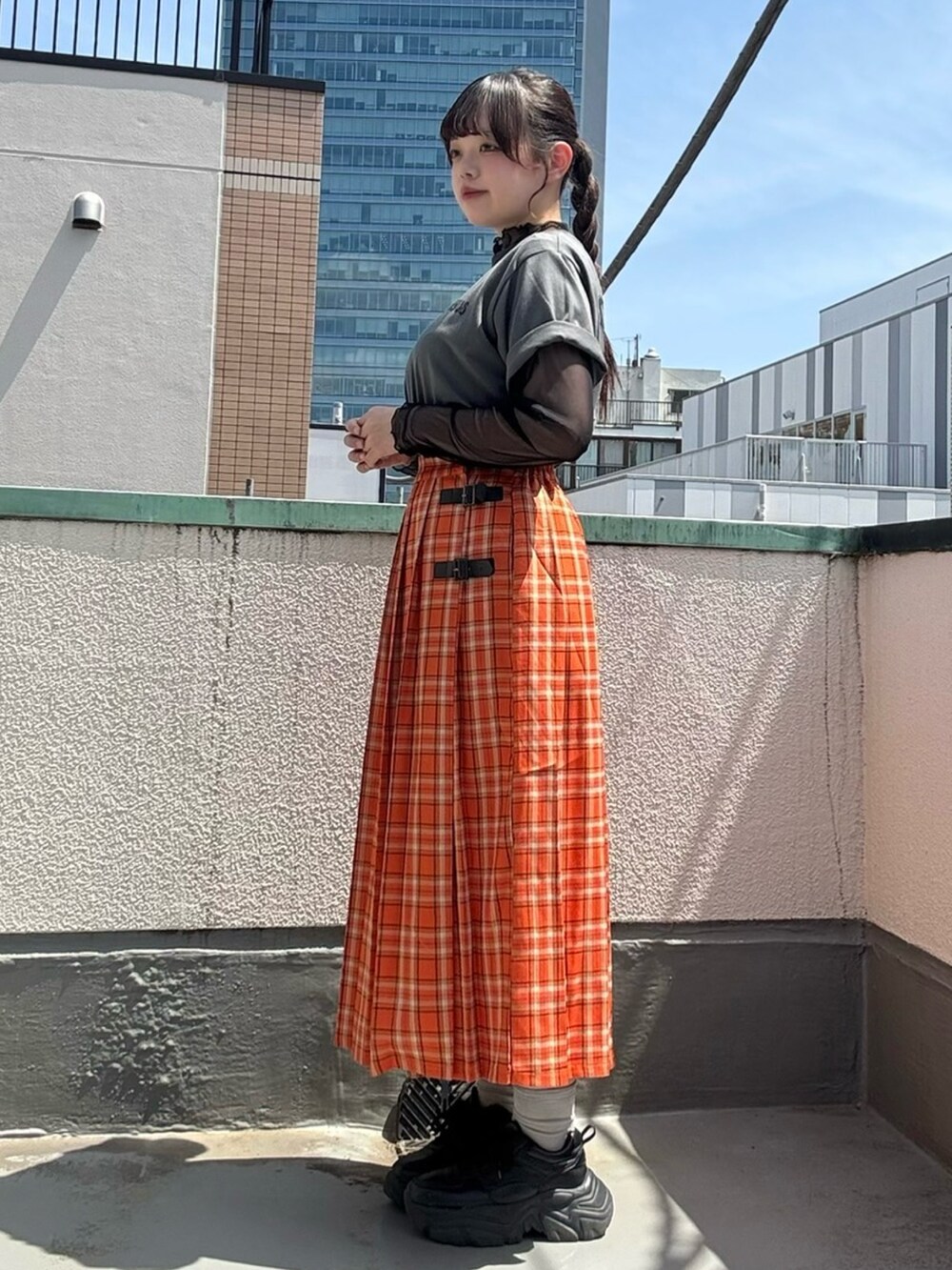 オレンジ系のスカート、ブラック系のTシャツ/カットソー、ブラック系のTシャツ/カットソーを着用したレディースの春コーディネートの4枚目の写真