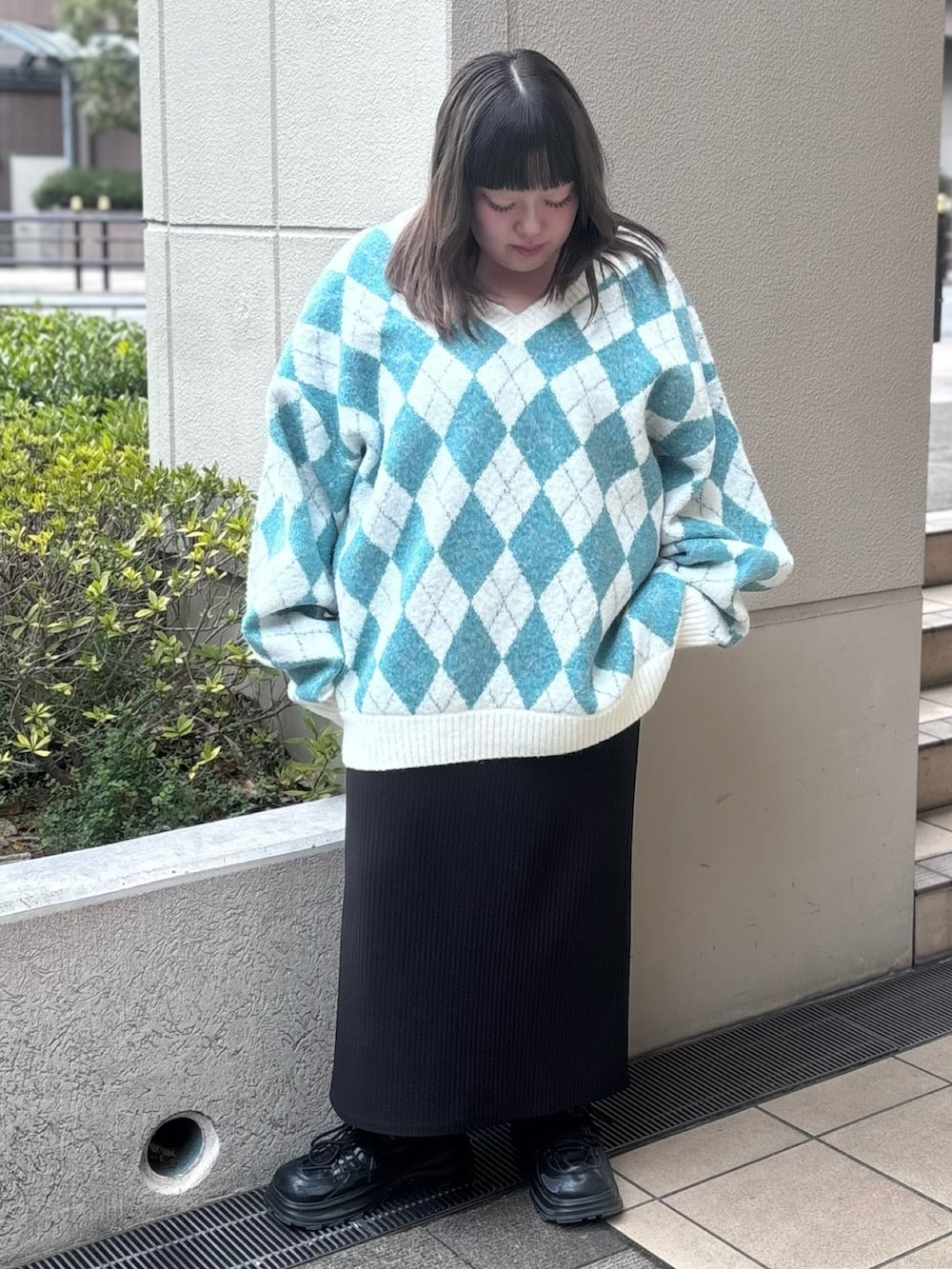 グリーン系のニット/セーター、ブラック系のスカートを着用したレディースの冬コーディネートの2枚目の写真