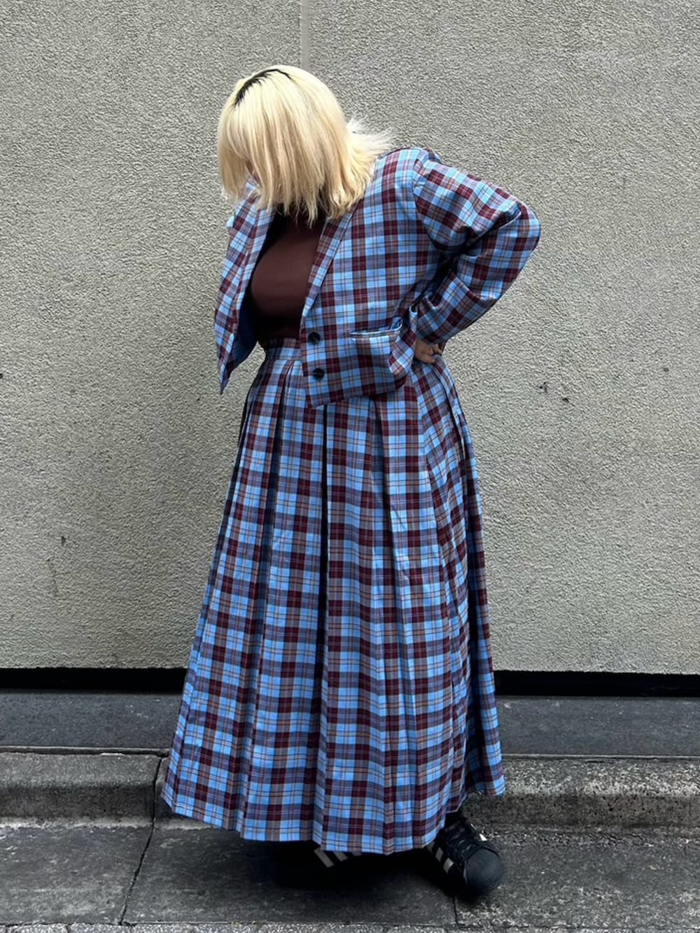 ブルー系のスカート、ブルー系のテーラードジャケット、ブラウン系のTシャツ/カットソーを着用したレディースの秋コーディネートの2枚目の写真