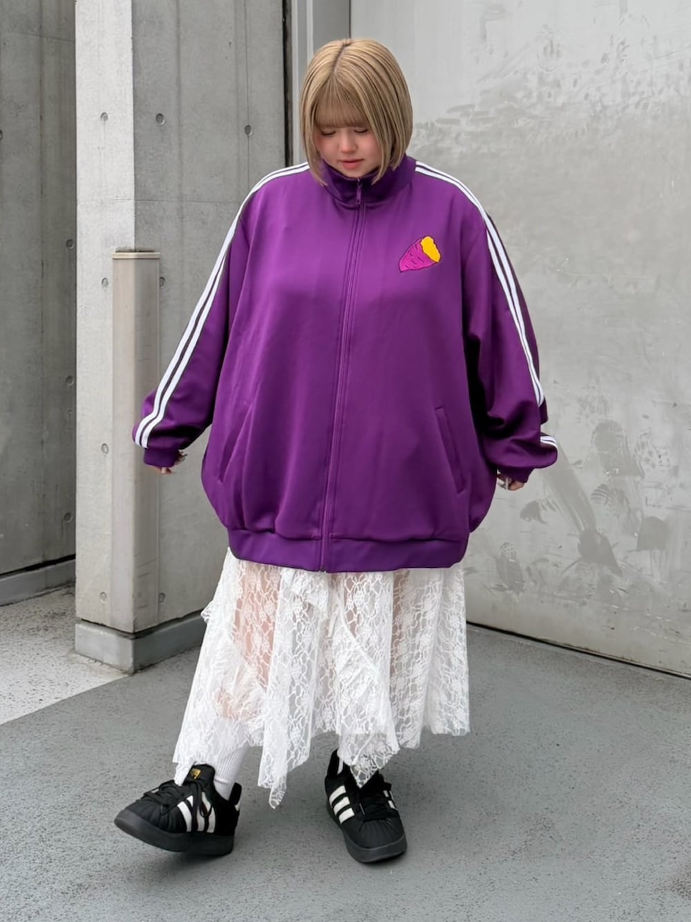 パープル系のジャージ、ホワイト系のスカートを着用したレディースの秋コーディネートの2枚目の写真
