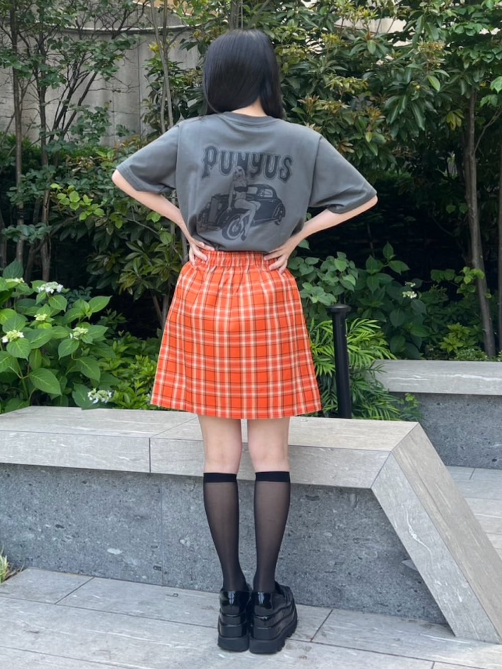 オレンジ系のスカート、ブラック系のTシャツ/カットソーを着用したレディースの春コーディネートの3枚目の写真