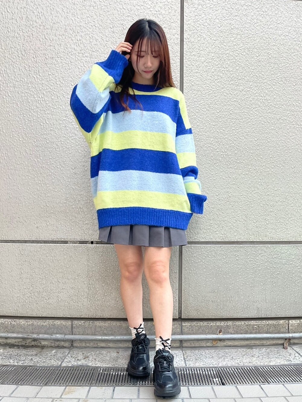 ブルー系のニット/セーター、グレー系のスカートを着用したレディースの秋コーディネートの2枚目の写真