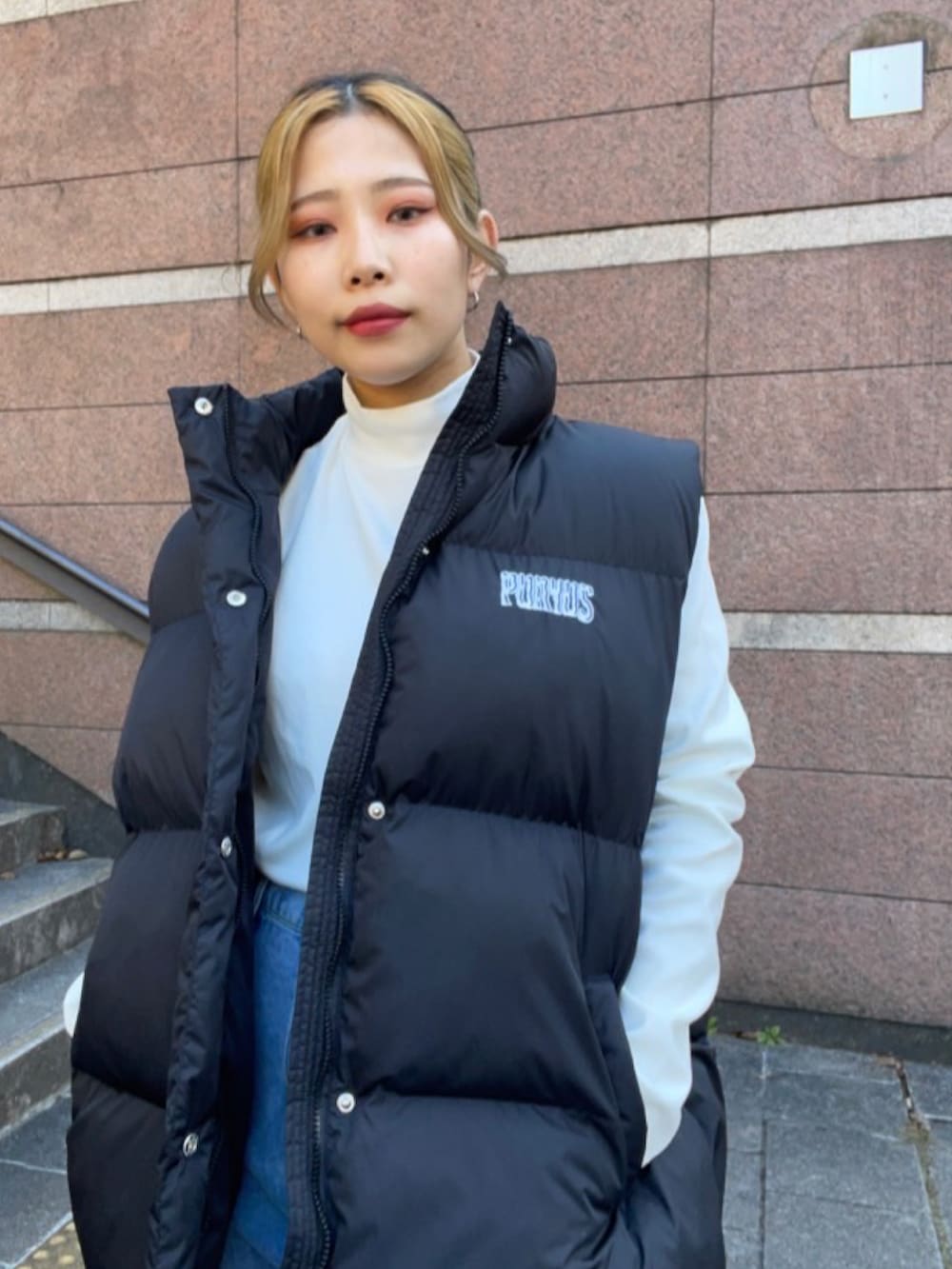 ブルー系のデニムパンツ、ホワイト系のTシャツ/カットソー、ブラック系のダウンベストを着用したレディースの冬コーディネートの2枚目の写真