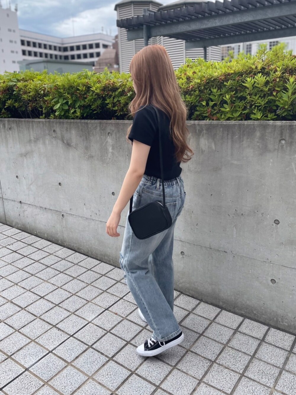 ブルー系のデニムパンツ、ブラック系のTシャツ/カットソー、ブラック系のショルダーバッグを着用したレディースの夏コーディネートの2枚目の写真