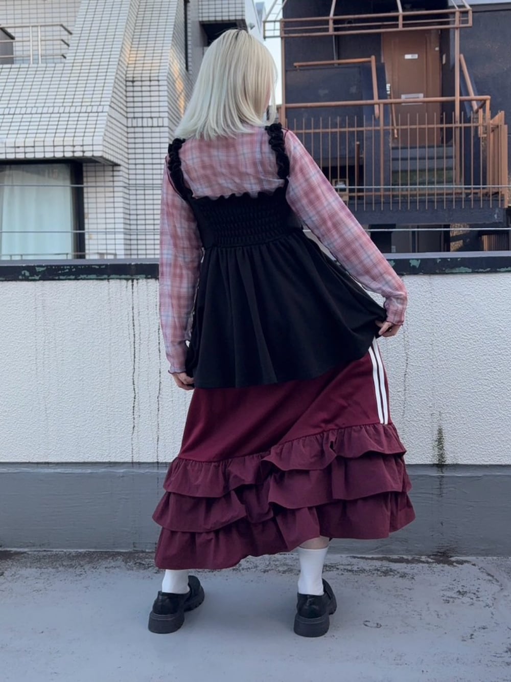 レッド系のスカート、ブラック系のワンピース、レッド系のTシャツ/カットソーを着用したレディースの秋コーディネートの2枚目の写真