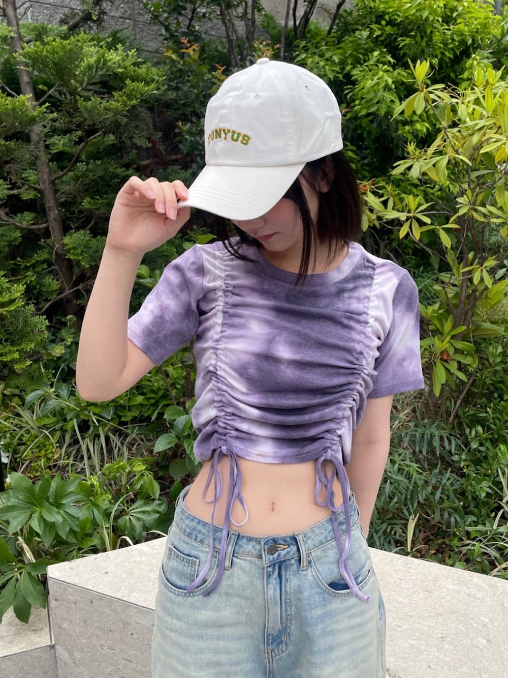 ブルー系のデニムパンツ、パープル系のTシャツ/カットソー、ホワイト系のキャップを着用したレディースの春コーディネートの4枚目の写真