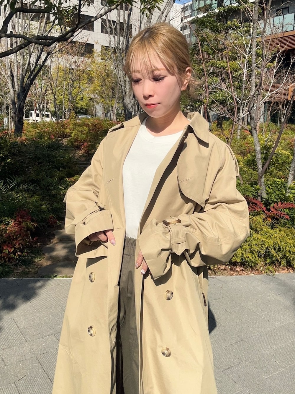 ベージュ系のトレンチコート、ベージュ系のスカートを着用したレディースの春コーディネートの2枚目の写真