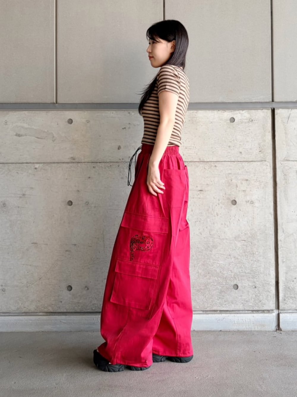 レッド系のカーゴパンツ、ブラウン系のTシャツ/カットソーを着用したレディースの夏コーディネートの3枚目の写真