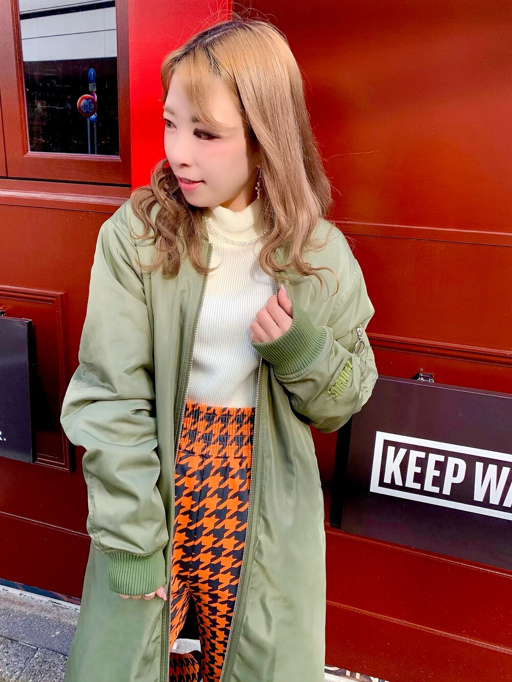 ホワイト系のニット/セーター、オレンジ系のその他パンツ、グリーン系のMA-1を着用したレディースの冬コーディネートの3枚目の写真