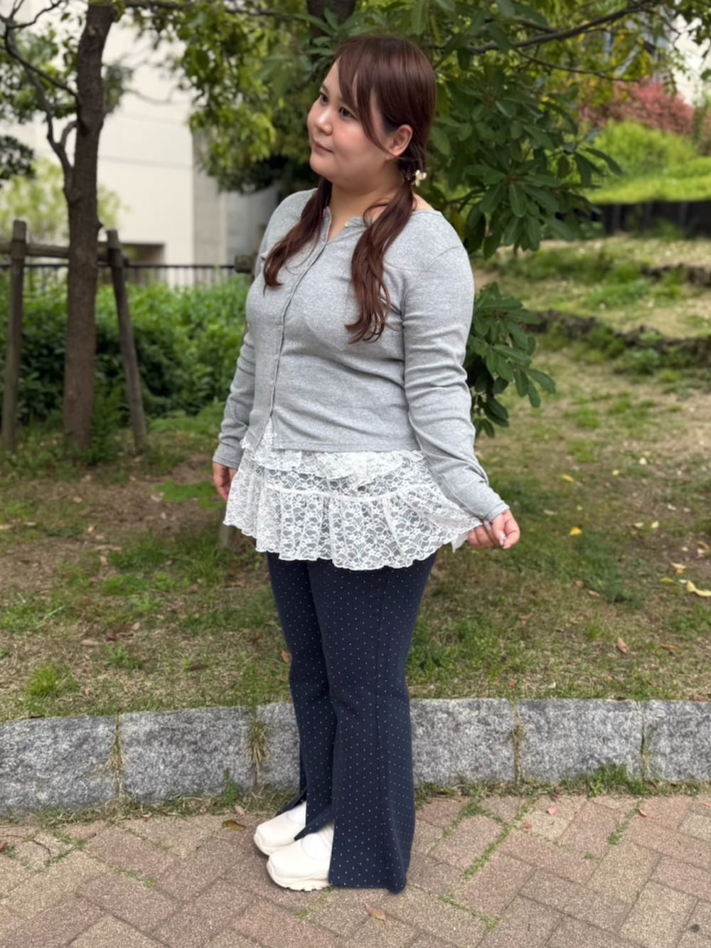 ブルー系のデニムパンツ、ホワイト系のワンピース、グレー系のカーディガン/ボレロを着用したレディースの春コーディネートの2枚目の写真