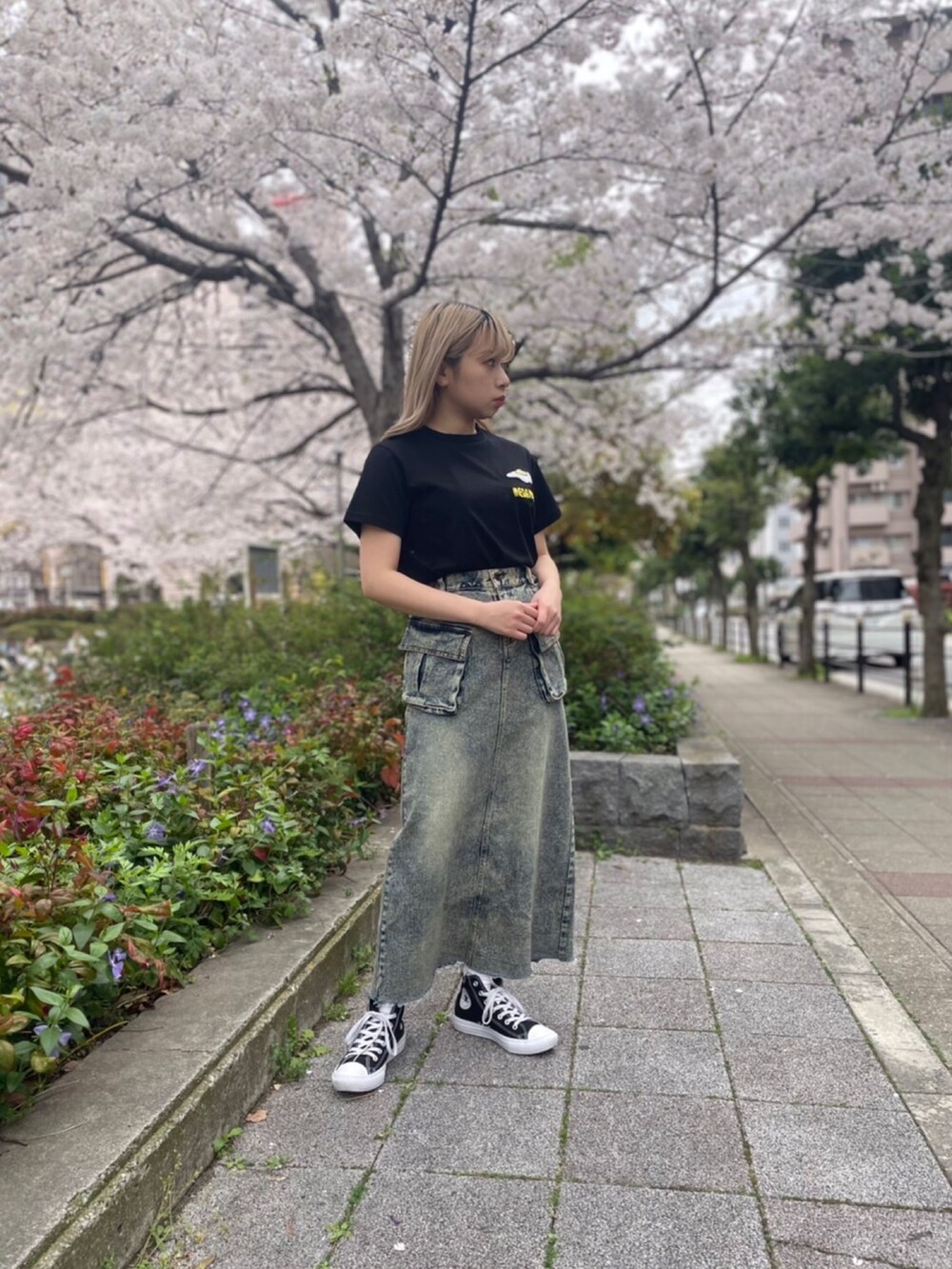 ブラック系のTシャツ/カットソー、ブルー系のデニムスカートを着用したレディースの春コーディネートの2枚目の写真