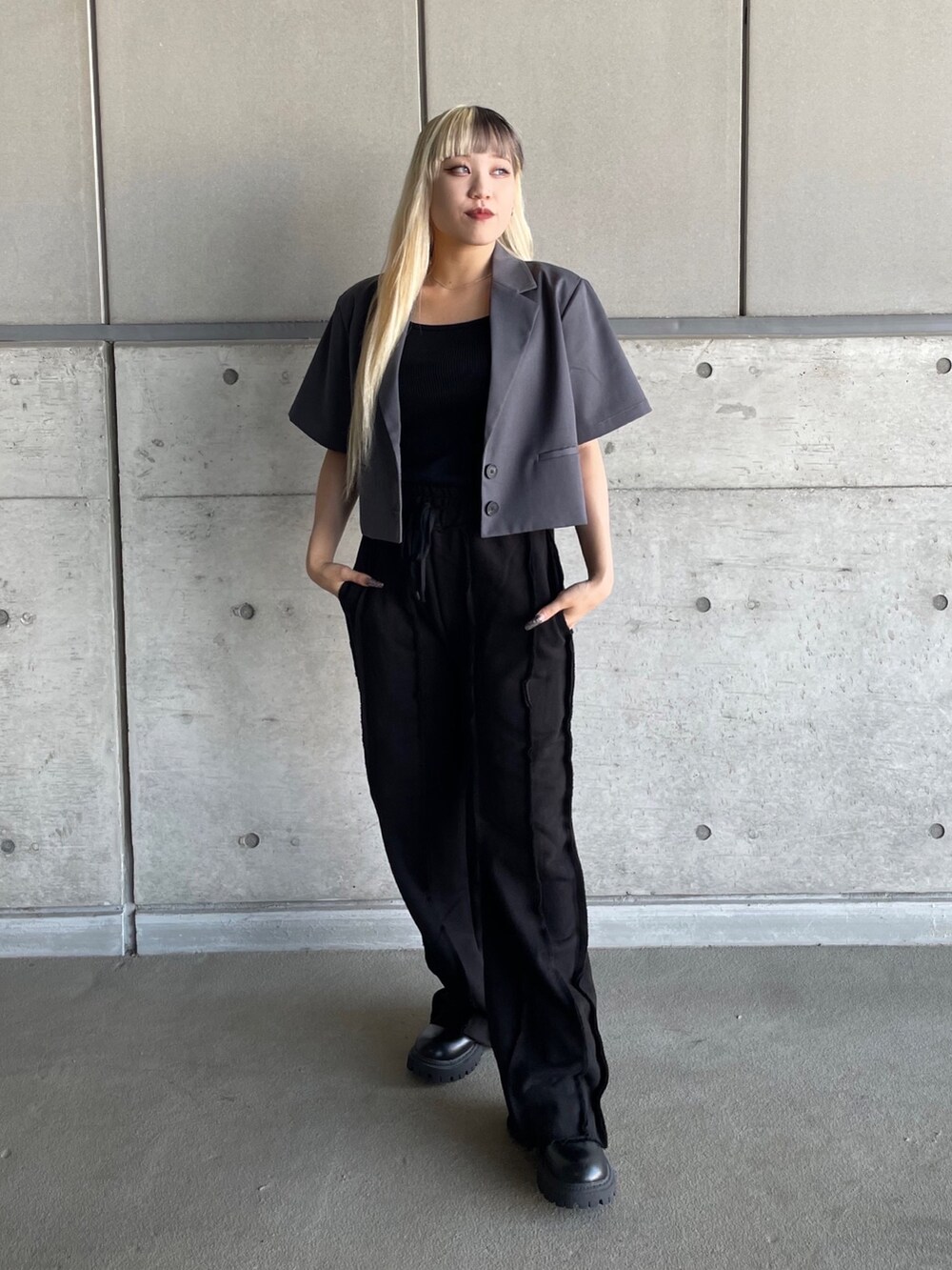 グレー系のテーラードジャケット、ブラック系のタンクトップ、ブラック系のスウェットパンツを着用したレディースの秋コーディネートの2枚目の写真