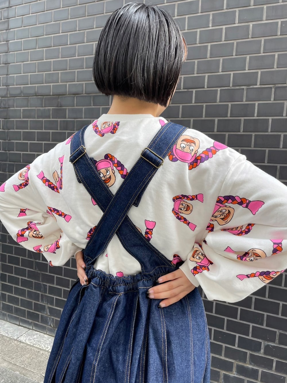 ブラック系のジャンパースカート、ホワイト系のスウェットを着用したレディースの秋コーディネートの2枚目の写真