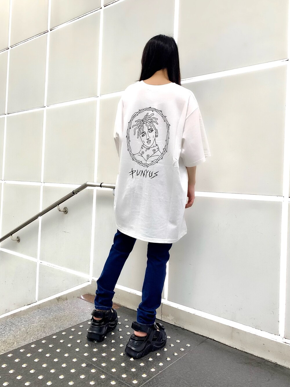 ブルー系のデニムパンツ、ブラック系のサンダル、ブラック系のTシャツ/カットソーを着用したレディースの夏コーディネートの2枚目の写真