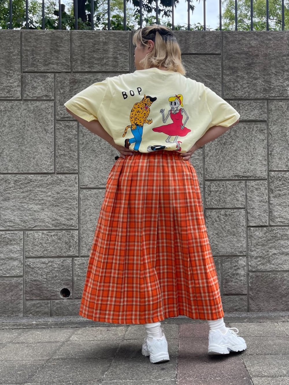 オレンジ系のスカート、イエロー系のTシャツ/カットソーを着用したレディースの夏コーディネートの2枚目の写真