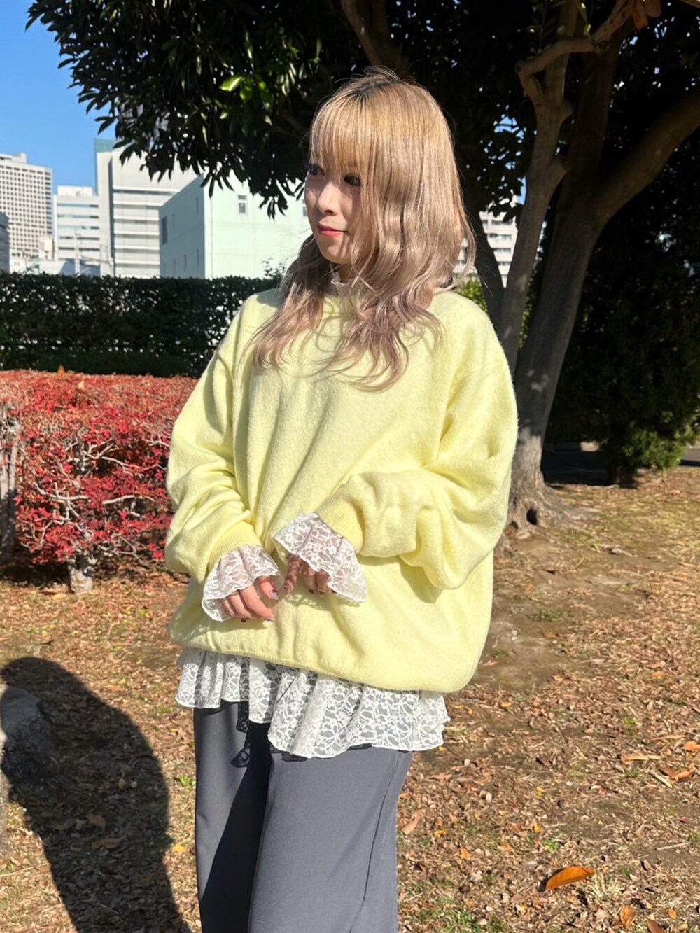 グレー系のスラックス、ホワイト系のTシャツ/カットソー、イエロー系のニット/セーターを着用したレディースの秋コーディネートの4枚目の写真