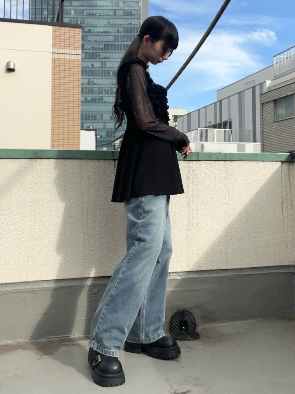 ブルー系のデニムパンツ、ブラック系のワンピース、ブラック系のTシャツ/カットソーを着用したレディースの秋コーディネートの3枚目の写真
