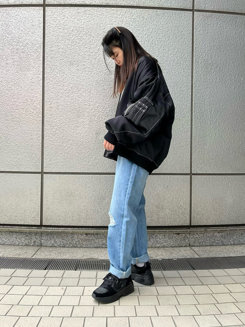 ブルー系のデニムパンツ、ブラック系のMA-1、ホワイト系のスウェットを着用したレディースの冬コーディネートの2枚目の写真