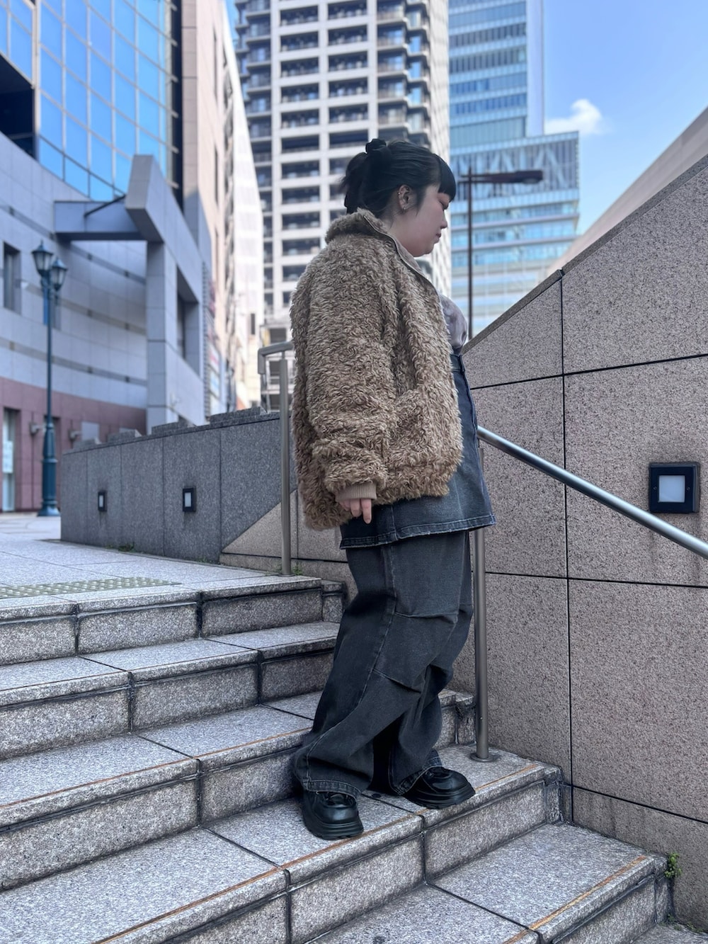 ブラック系のデニムパンツ、ブラック系のデニムスカート、ブラウン系のブルゾンを着用したレディースの冬コーディネートの2枚目の写真