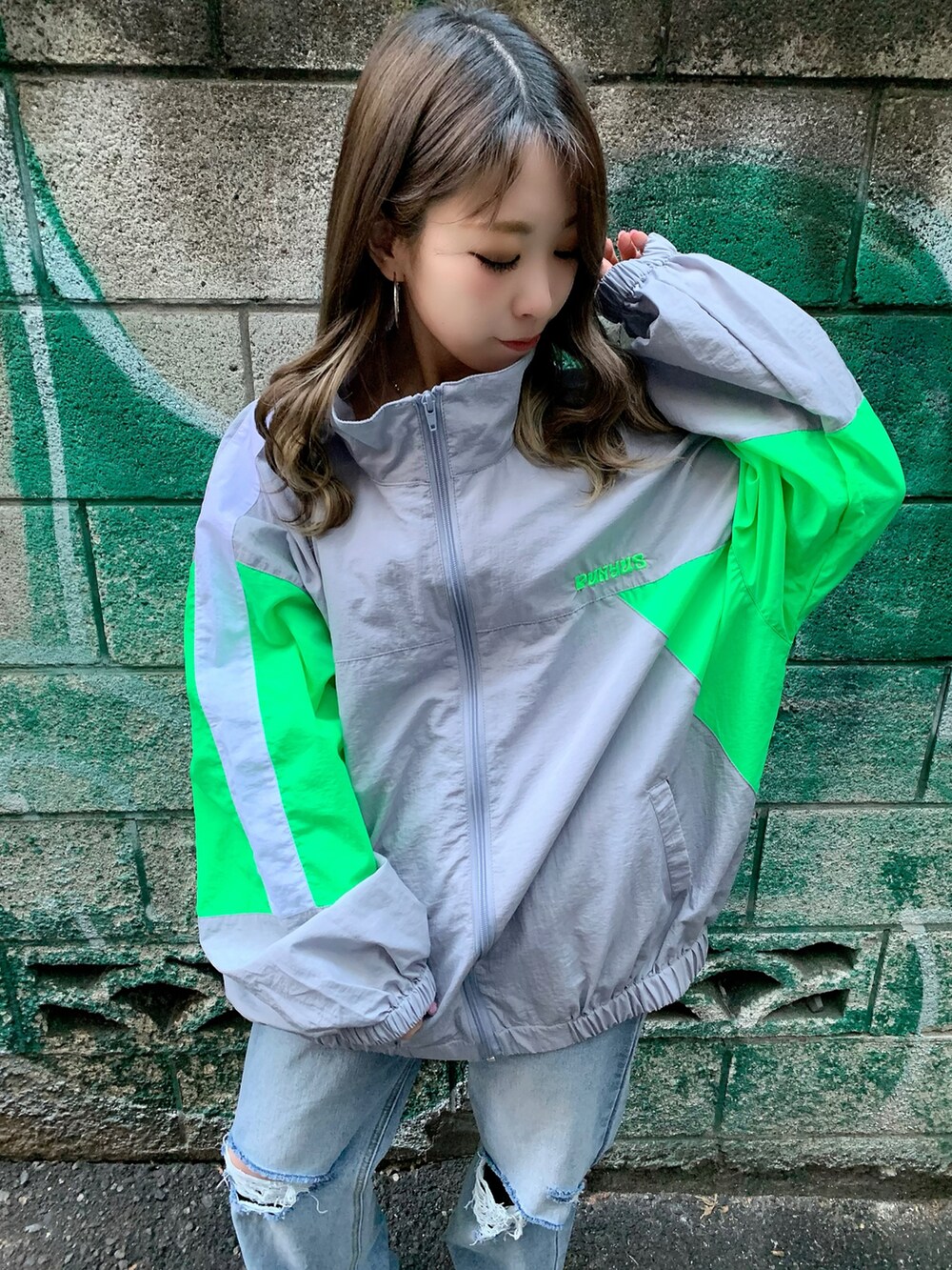 グレー系のナイロンジャケット、ブルー系のデニムパンツ、ホワイト系のスニーカーを着用したレディースの冬コーディネートの2枚目の写真