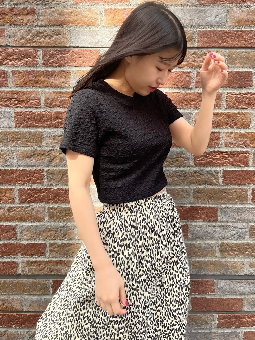 ブラック系のTシャツ/カットソー、ホワイト系のスカート、ブラック系のサンダルを着用したレディースの春コーディネートの2枚目の写真