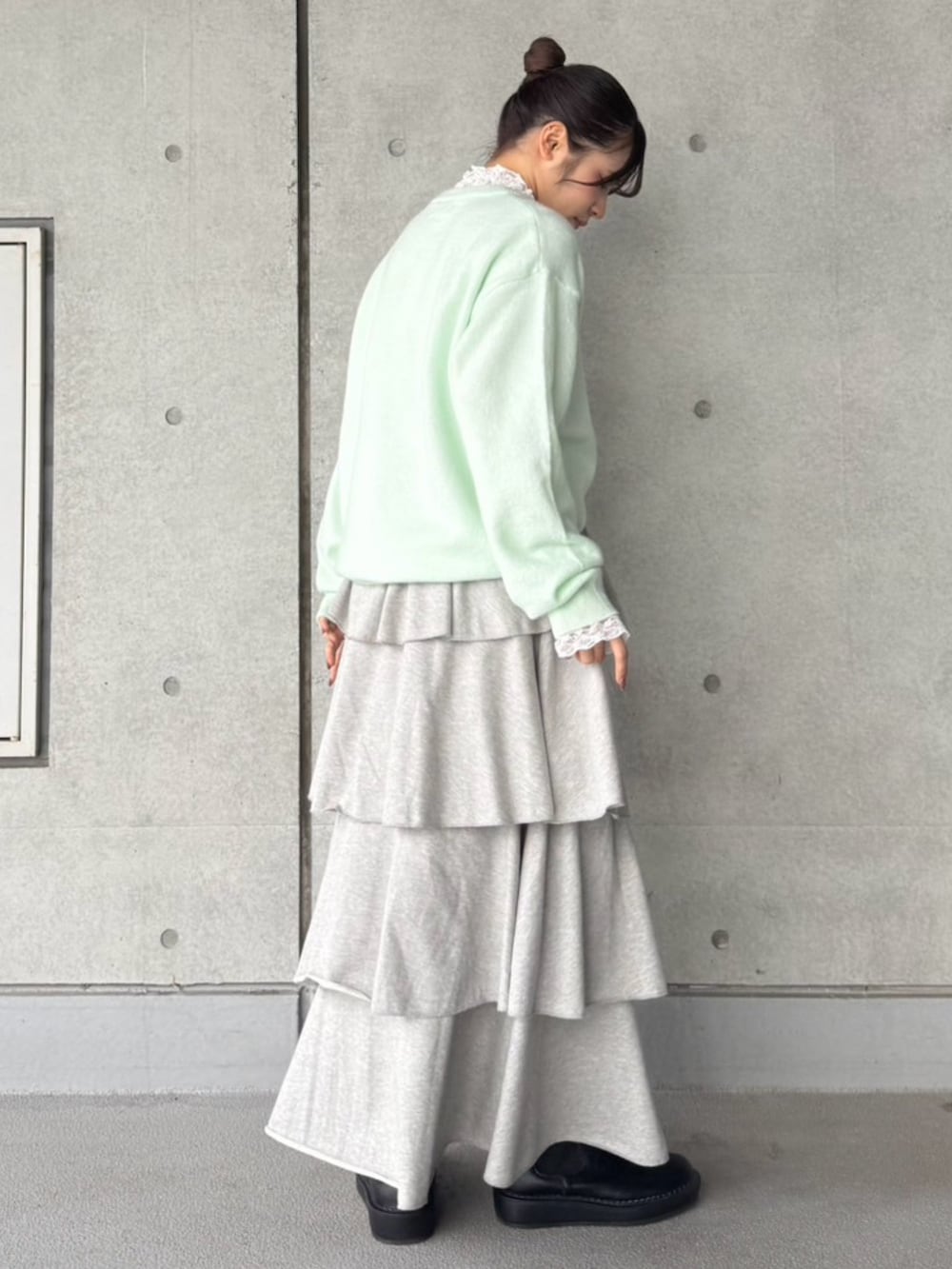 グレー系のスカート、グリーン系のニット/セーター、ホワイト系のTシャツ/カットソーを着用したレディースの冬コーディネートの4枚目の写真