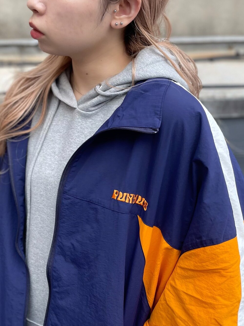 グレー系のパーカー、ブルー系のナイロンジャケットを着用したレディースの秋コーディネートの2枚目の写真