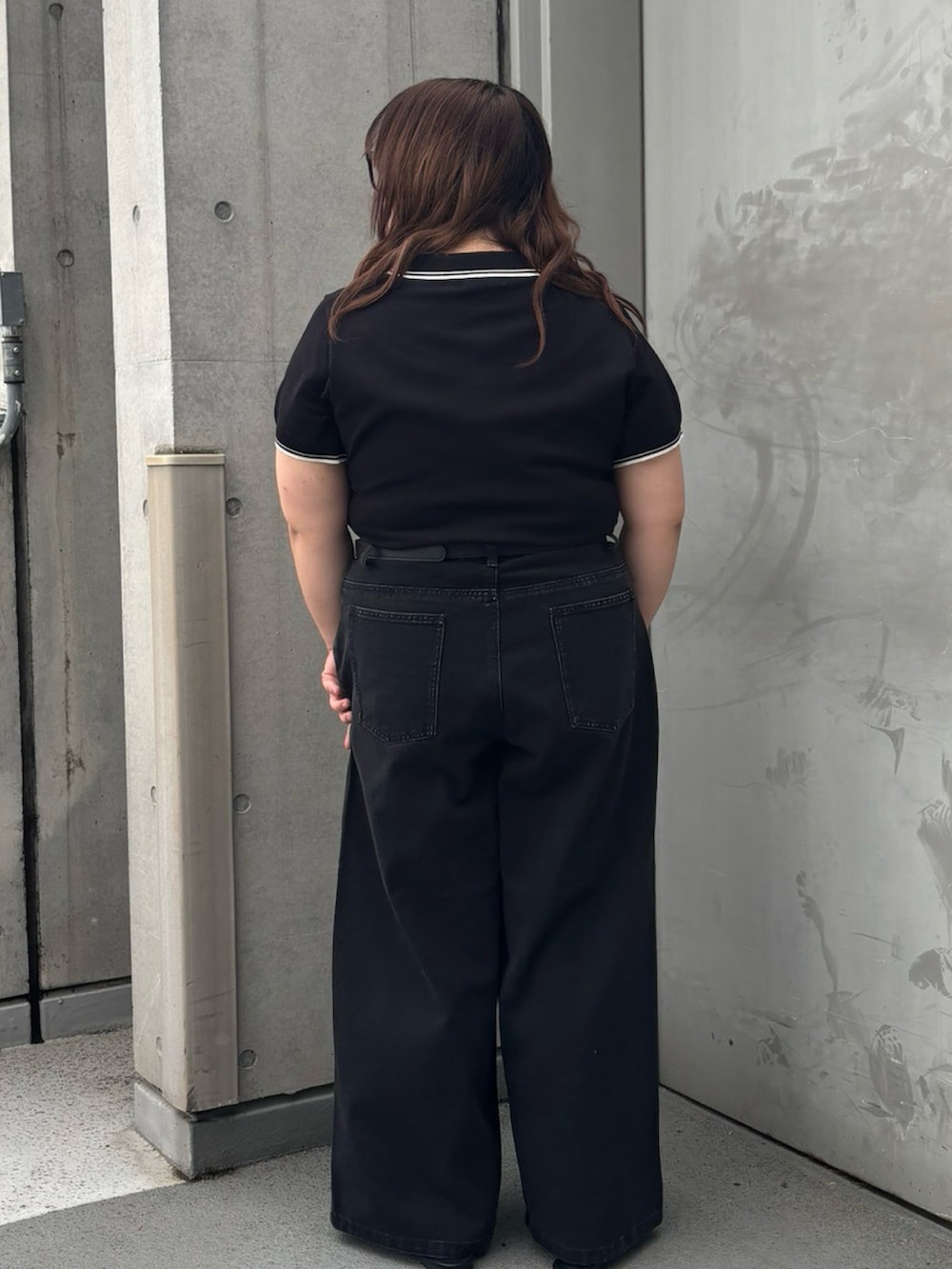 ブラック系のデニムパンツ、ブラック系のポロシャツ、ブラック系のベルトを着用したレディースの夏コーディネートの4枚目の写真