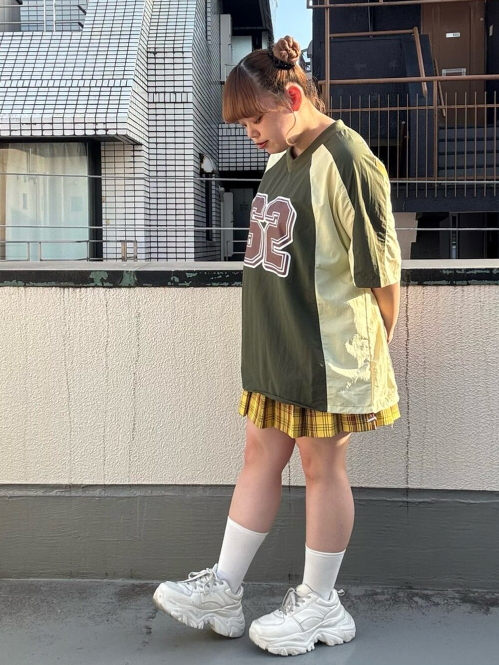 グリーン系のTシャツ/カットソー、イエロー系のスカートを着用したレディースの秋コーディネートの2枚目の写真