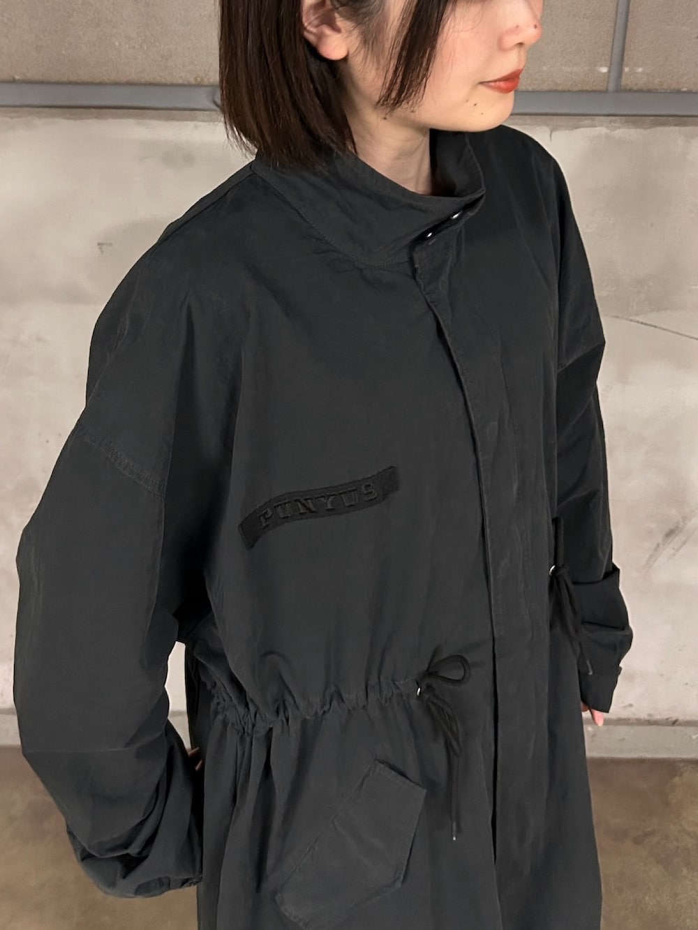 ブラック系のモッズコート、ブルー系のデニムパンツ、レッド系のカーディガン/ボレロを着用したレディースの春コーディネートの6枚目の写真