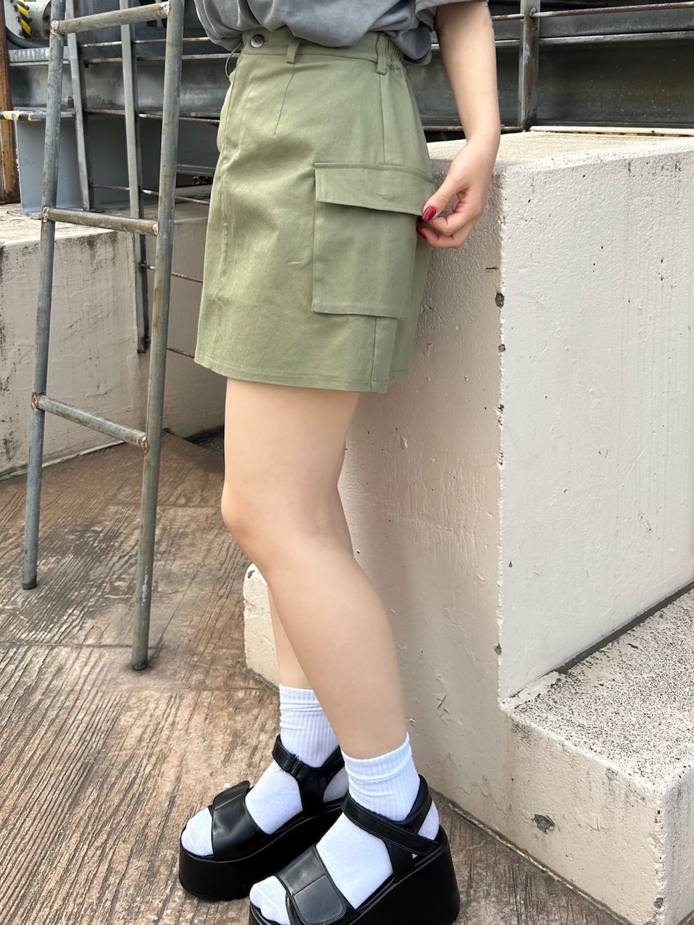 グリーン系のスカート、ブラック系のTシャツ/カットソー、ブラック系のサンダルを着用したレディースの夏コーディネートの4枚目の写真