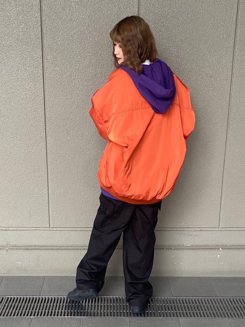 ブラック系のカーゴパンツ、パープル系のパーカー、オレンジ系のMA-1を着用したレディースの冬コーディネートの2枚目の写真