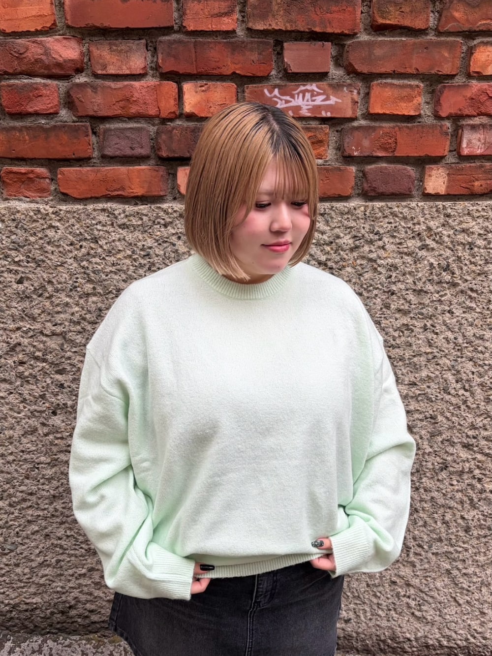 ブラック系のデニムスカート、グリーン系のニット/セーターを着用したレディースの冬コーディネートの4枚目の写真