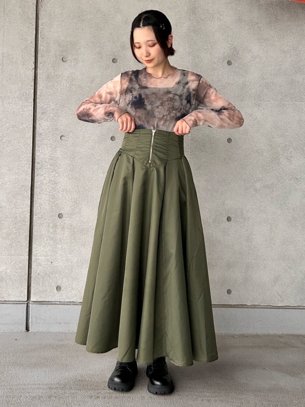 グリーン系のスカート、ブラウン系のTシャツ/カットソーを着用したレディースの夏コーディネートの2枚目の写真