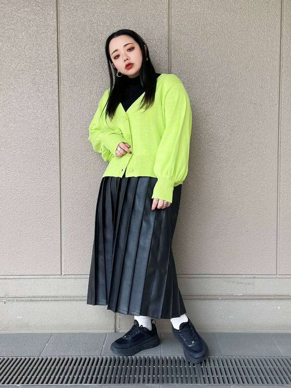 ブラック系のスカート、ブラック系のTシャツ/カットソー、グリーン系のカーディガン/ボレロを着用したレディースの春コーディネートの2枚目の写真