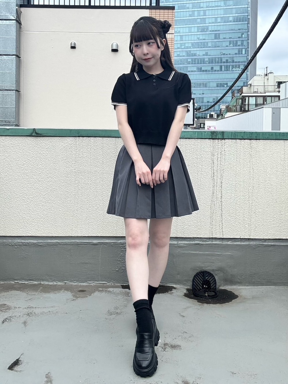 グレー系のスカート、ブラック系のポロシャツを着用したレディースの夏コーディネートの3枚目の写真